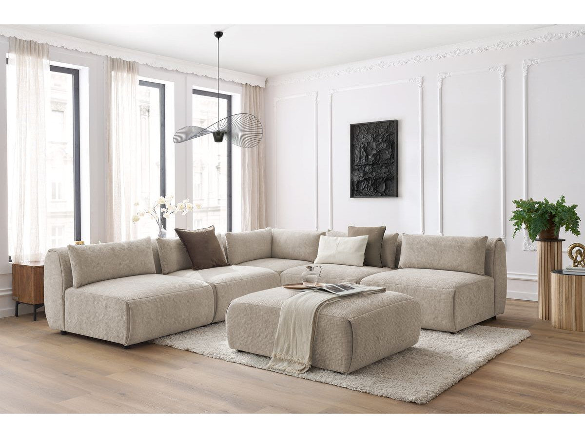 Kampinė sofa JEANNE, 4 moduliai + kampas + pufas, smėlinė moderniame interjere