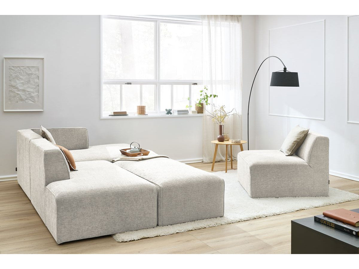 Kampinė modulinė sofa su pufu ir smėlinė svetainės interjere